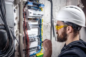 male-electrician-works-switchboard-with-electrical-connecting-cable-connects-equipment-with-tools